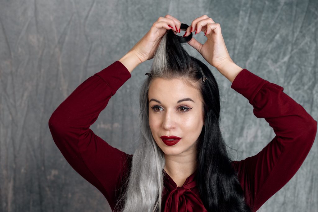 Frau rollt Haarsträhne zur Victory Roll