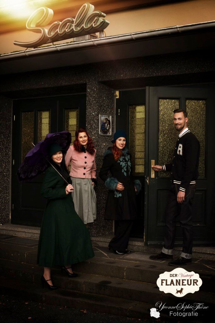 Gruppe von Menschen in Vintage Wintermode betritt ein Kino